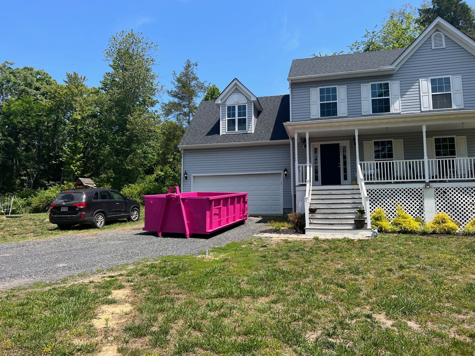 a large white house with a pink dumpster in front of it .
