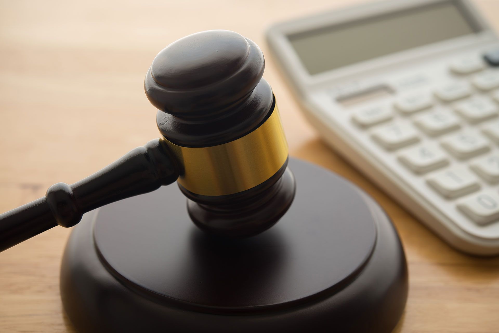 Gavel hammer judge and white calculator on wooden table background. Tax law, financial law or regulation, creative accounting, corruption, bribe, bankruptcy, penalty and so on concept