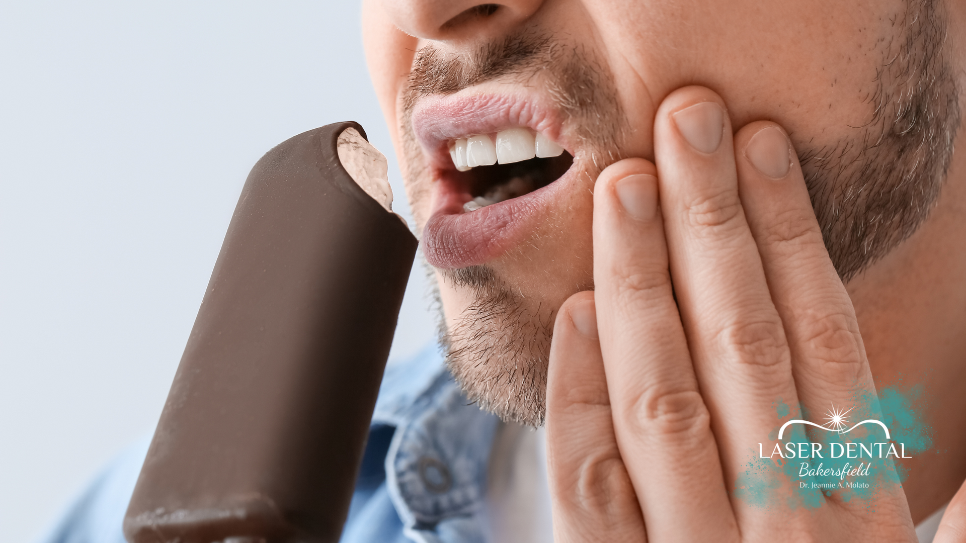 Man experiencing tooth sensitivity while eating ice cream.