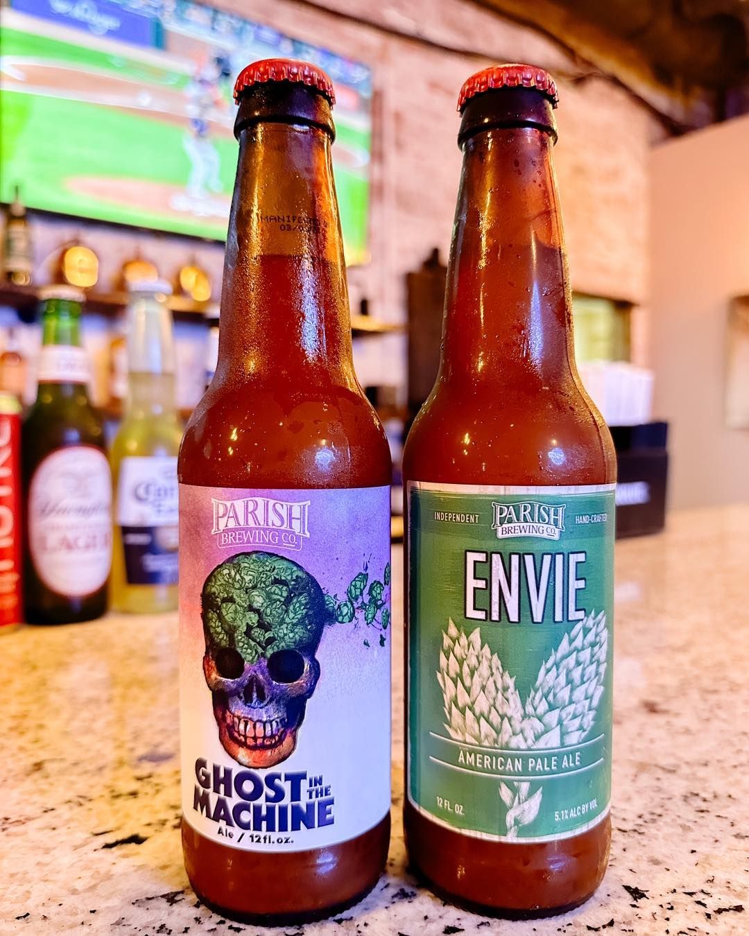 Two bottles of beer are sitting next to each other on a counter.