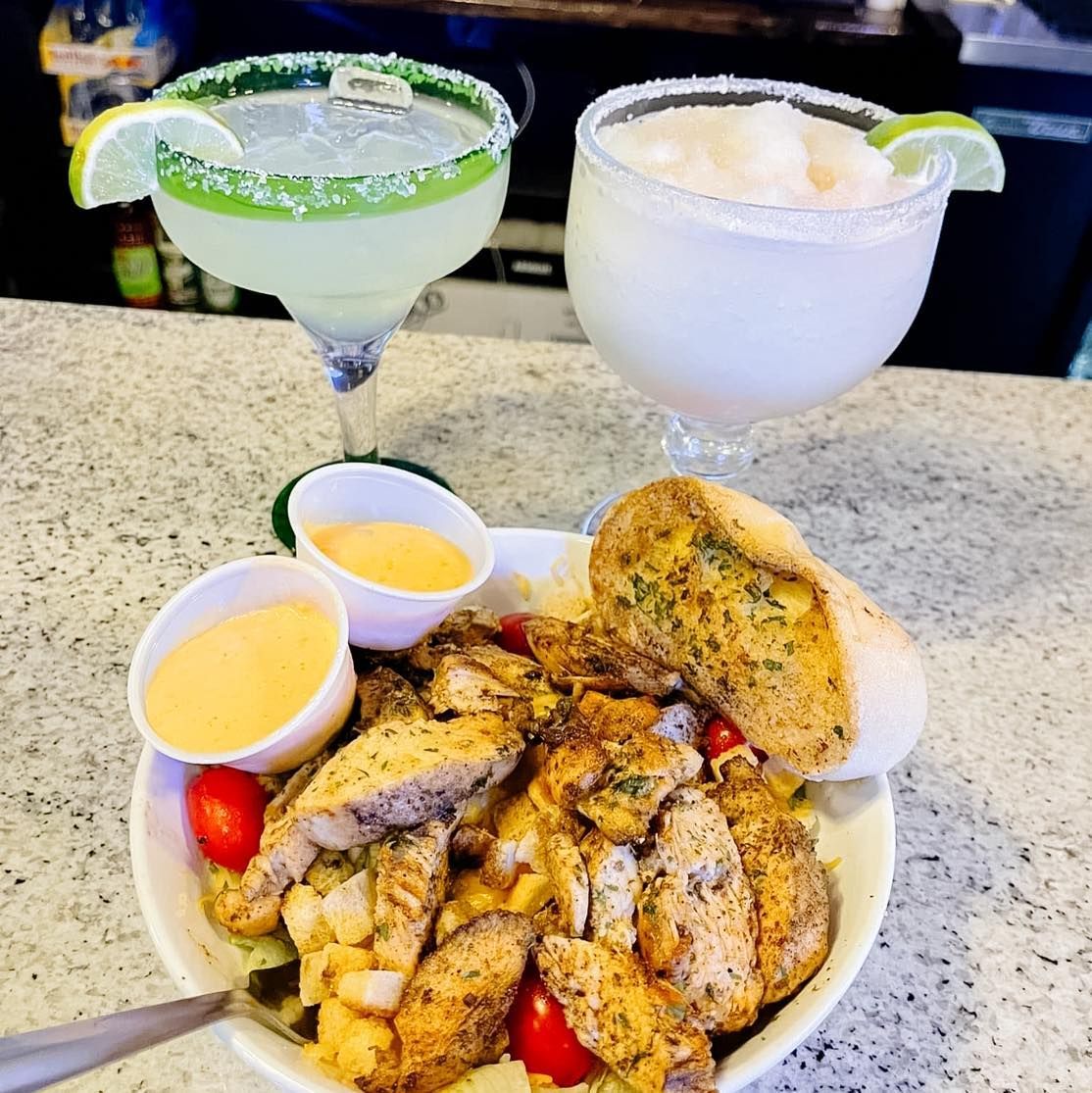 A bowl of food and two drinks on a table