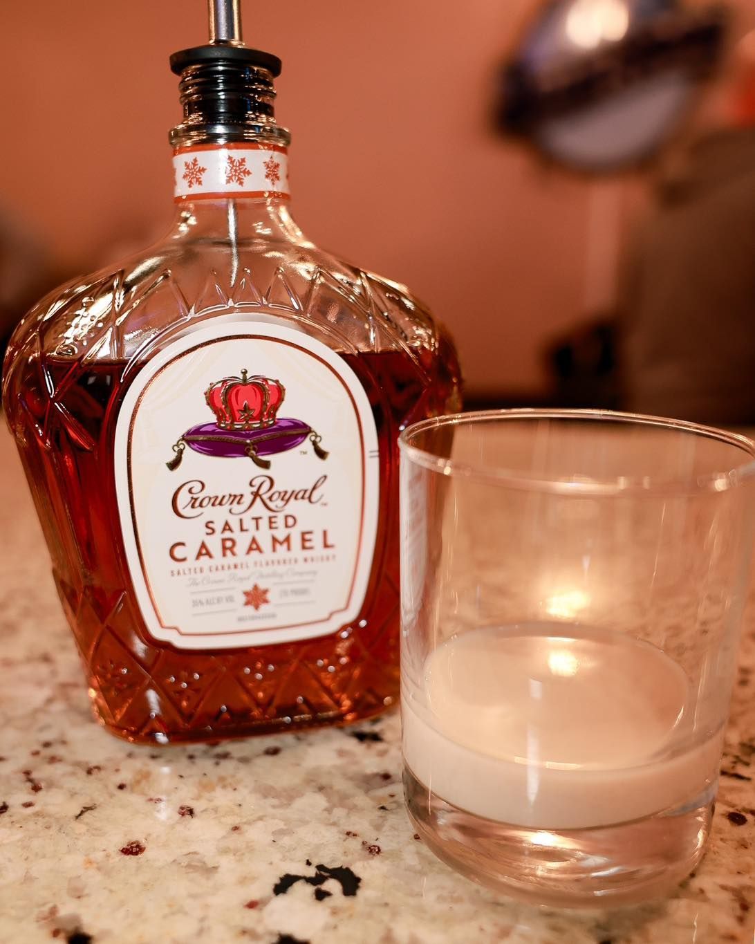 A bottle of crown royal salted caramel next to a glass