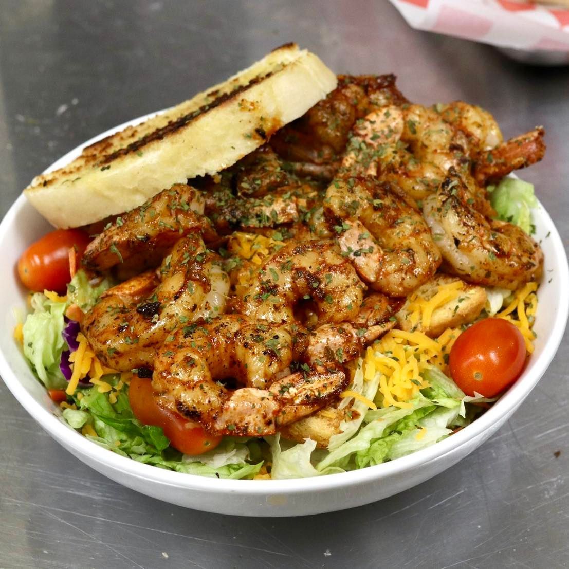 A bowl of shrimp salad with tomatoes and cheese