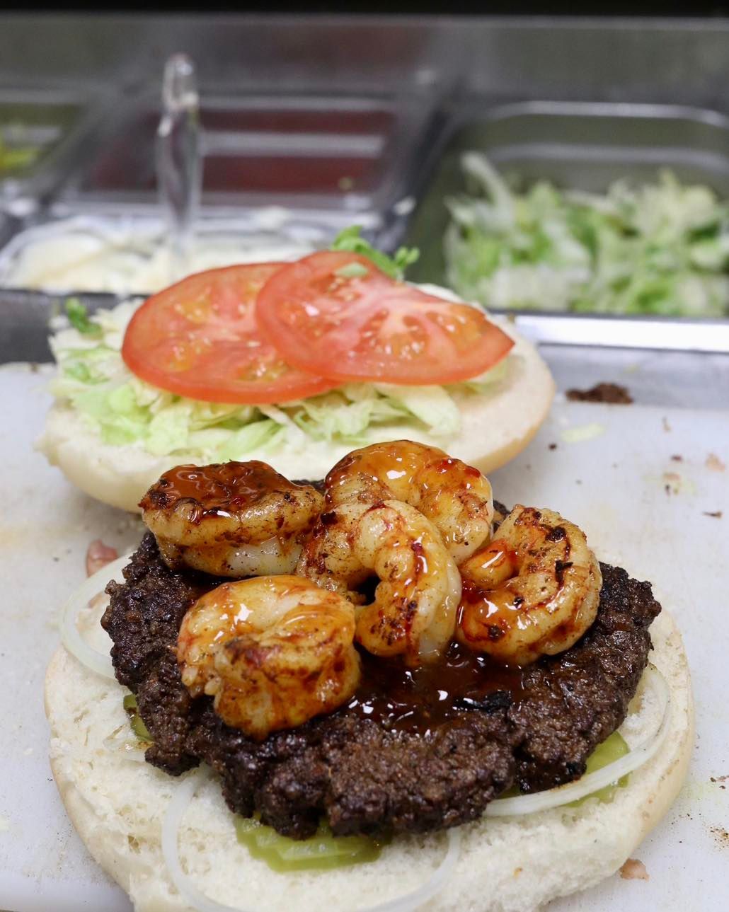 A hamburger with shrimp and tomatoes on a bun