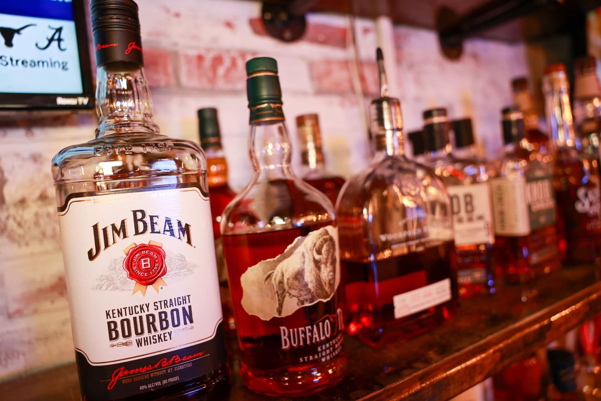 A bottle of jim beam bourbon is sitting on a shelf next to other bottles of bourbon.