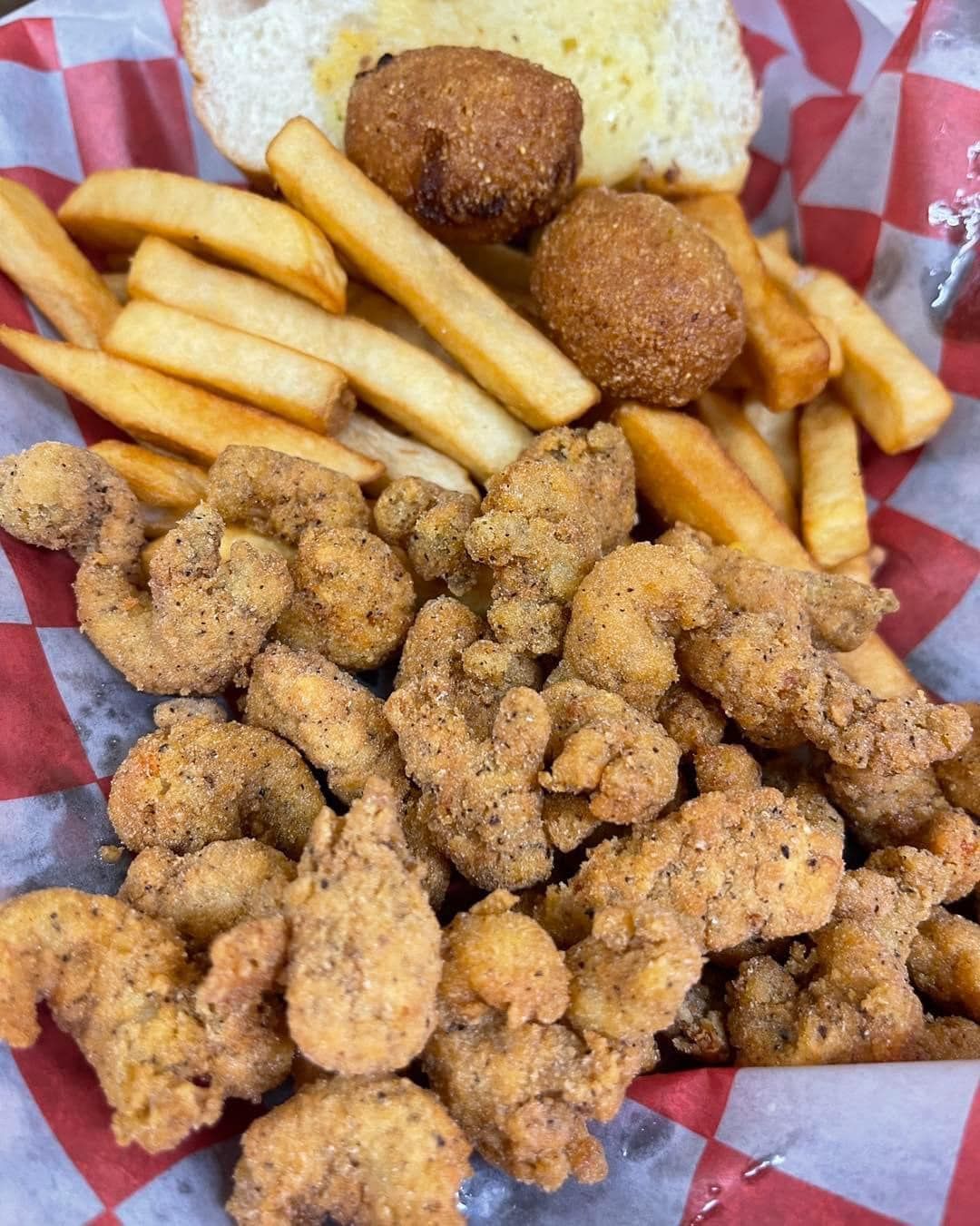 A basket of fried shrimp and french fries on a checkered paper.