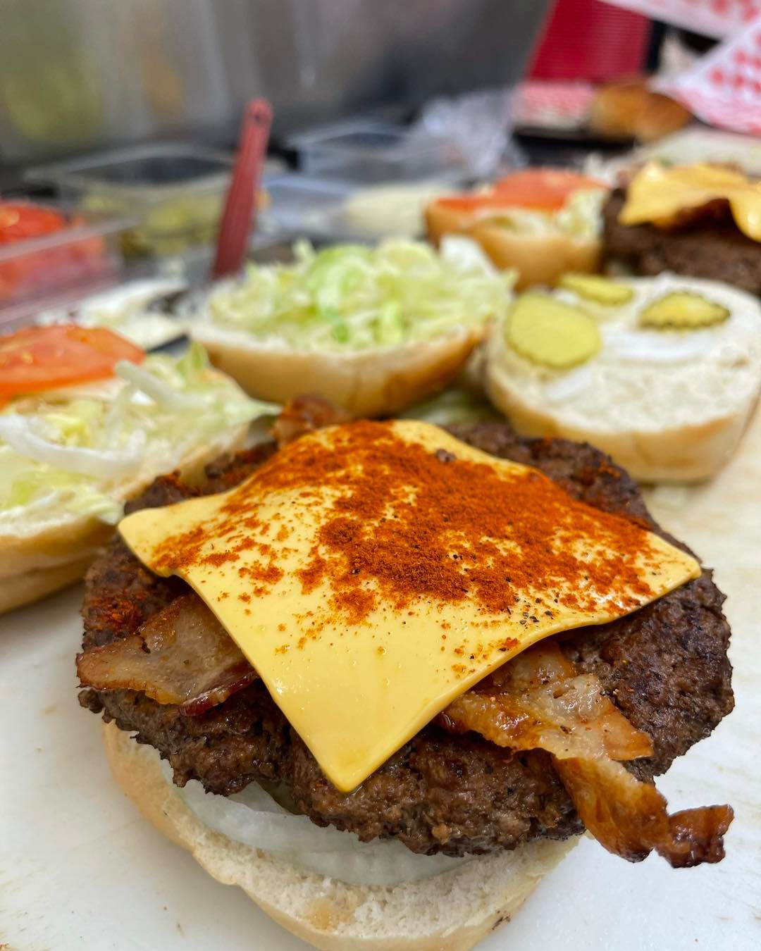 A close up of a hamburger with cheese and bacon on a bun.
