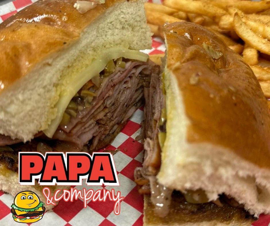 A papa & company sandwich and french fries on a checkered napkin