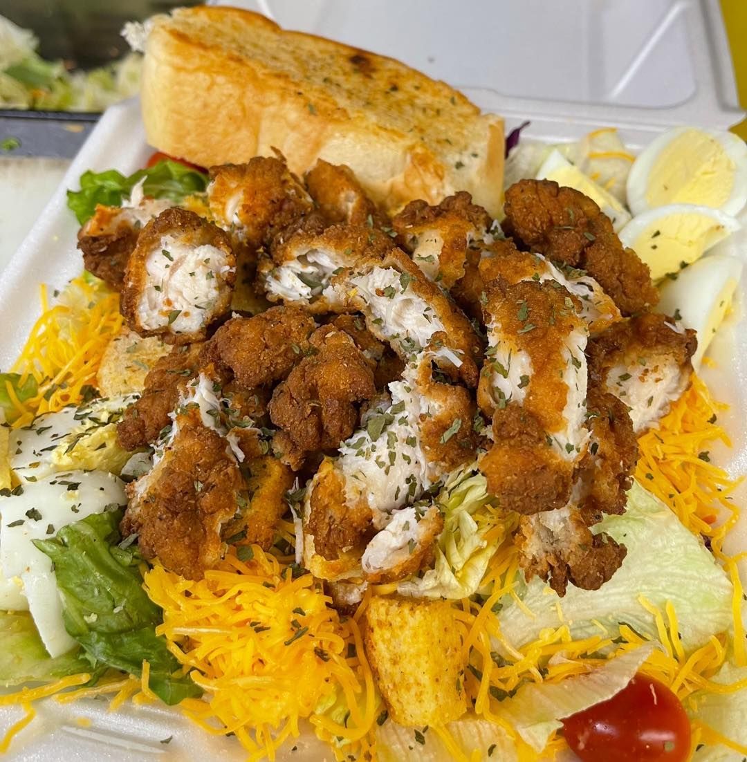 A close up of a fried chicken salad in a styrofoam container.