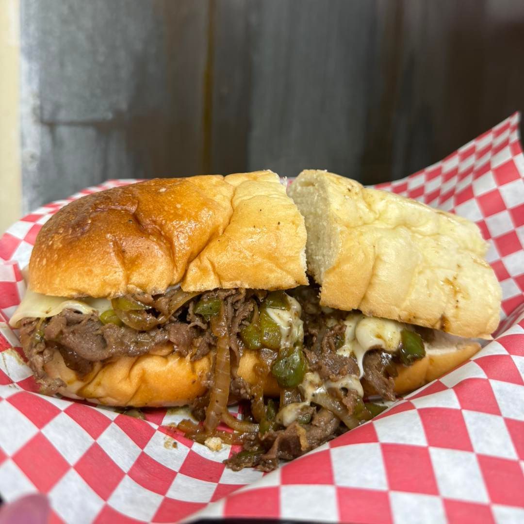 A sandwich is sitting on a checkered paper on a plate.