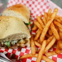 A sandwich and french fries on a checkered paper on a table.