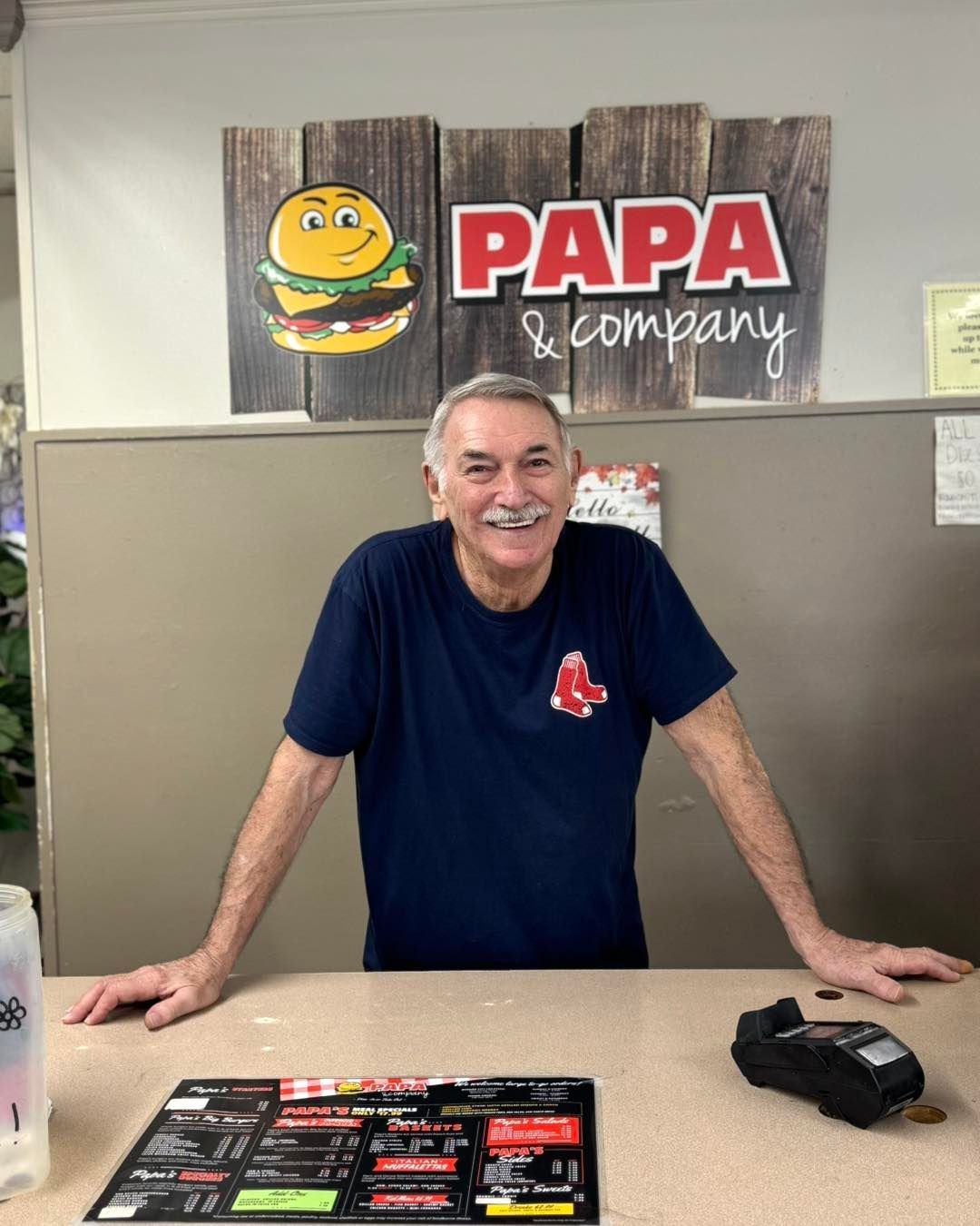 A man is standing in front of a papa & company sign.