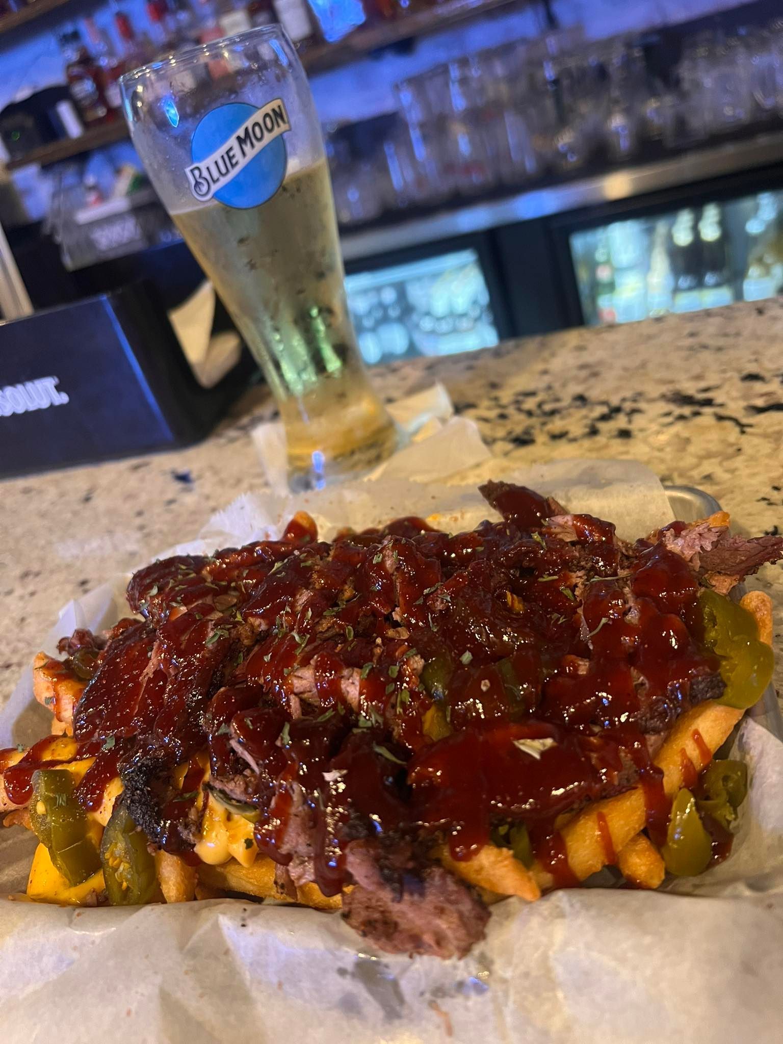 A close up of a plate of food on a table next to a glass of beer.