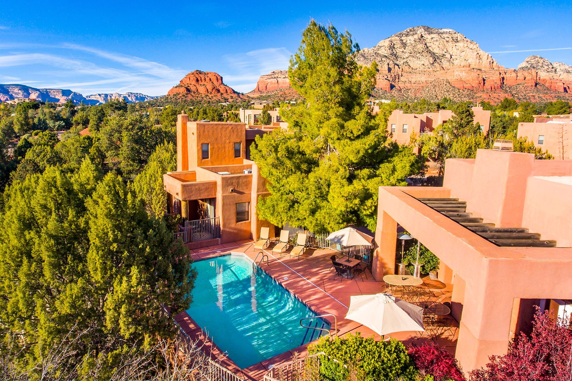 An aerial view of a large house with a swimming pool surrounded by trees and mountains.