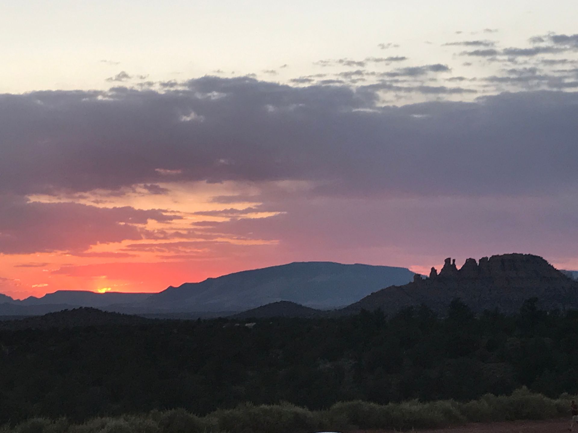A sunset over a mountain range with trees in the foreground