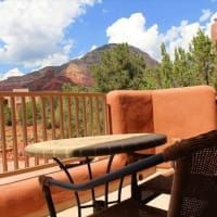 A table and chairs on a balcony with mountains in the background.