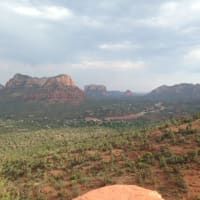 A person is holding a rock in front of a mountain range.