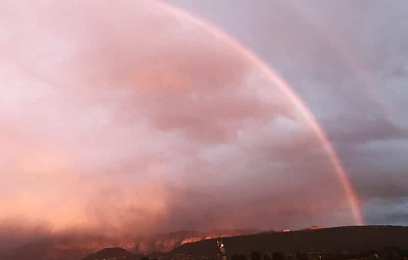 A rainbow is visible in the sky during a storm.
