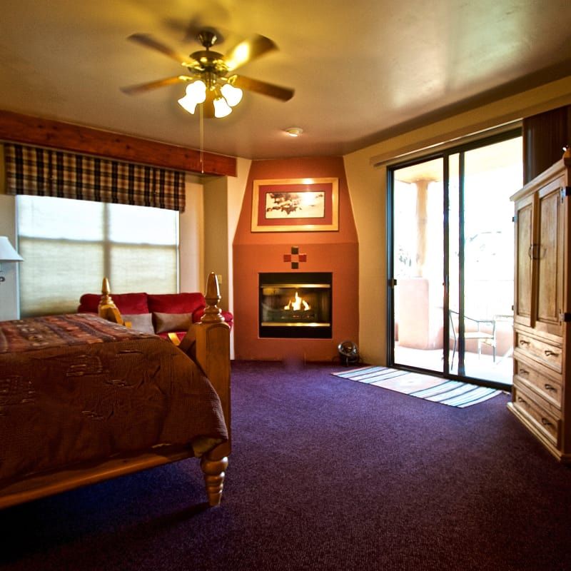 A bedroom with a fireplace and a ceiling fan