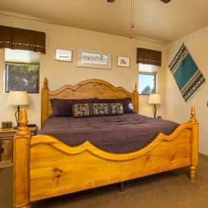 A bedroom with a wooden bed and purple sheets