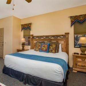 A hotel room with a king size bed and a ceiling fan.