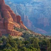 A view of a canyon with a mountain in the background and trees in the foreground.