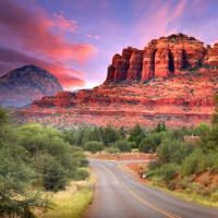 A road going through a desert landscape with mountains in the background.