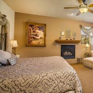 A bedroom with a fireplace and a painting on the wall above the bed