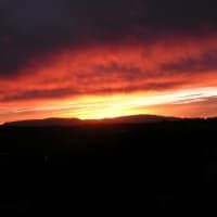 The sun is setting over the mountains in the distance.