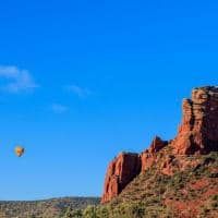 A hot air balloon is flying over a mountain.