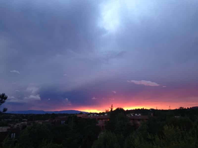 A sunset over a city with trees in the foreground