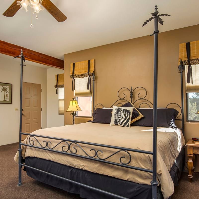 A bedroom with a four poster bed and a ceiling fan
