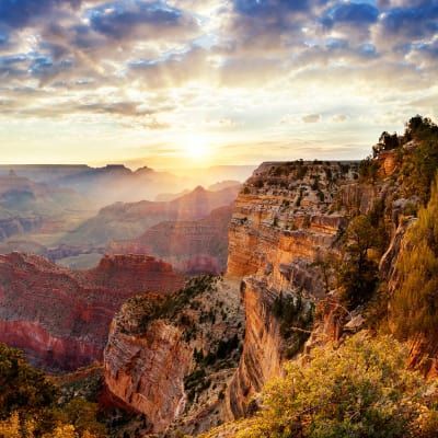 The sun is shining through the clouds over the grand canyon.