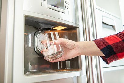 Woman's Hand Holds Glass and Uses Refrigerator — Carroll County, MD — Alford Plumbing & Heating, Inc.