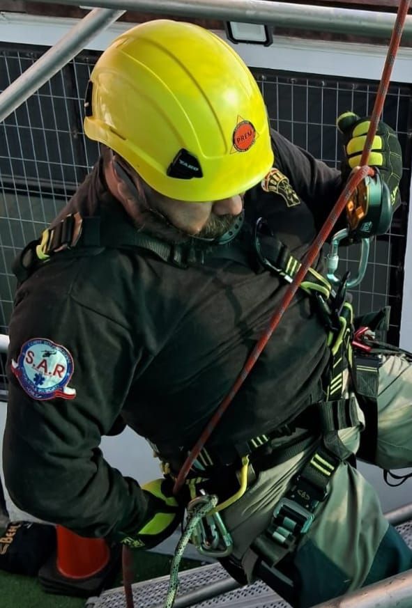 El instructor demuestra el equipo de seguridad a un grupo de personas que usan arneses en un entorno de capacitación.