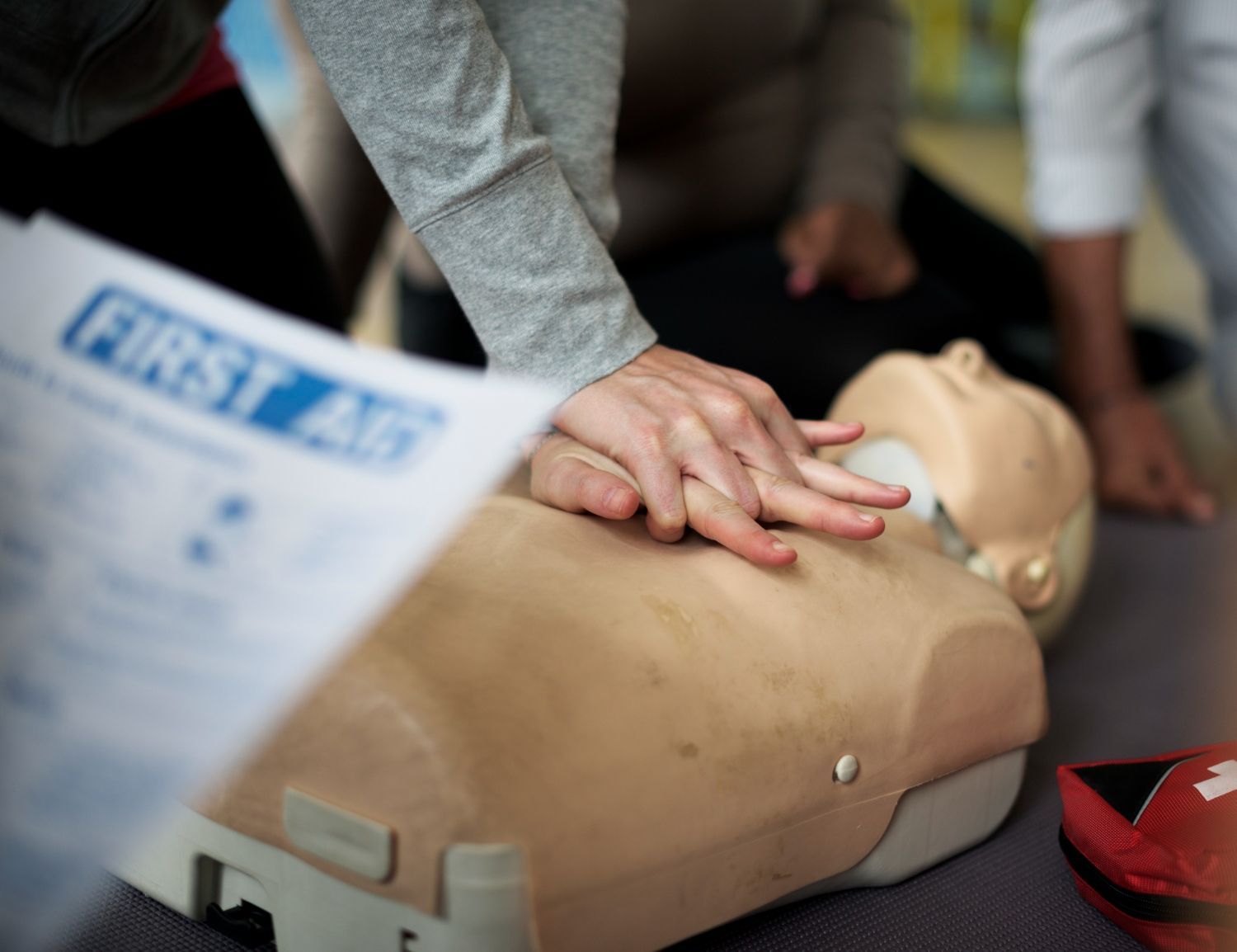 Persona practicando RCP en un maniquí de entrenamiento durante un curso de primeros auxilios.
