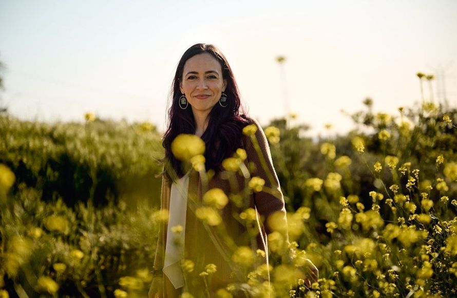 A woman is standing in a field of yellow flowers.