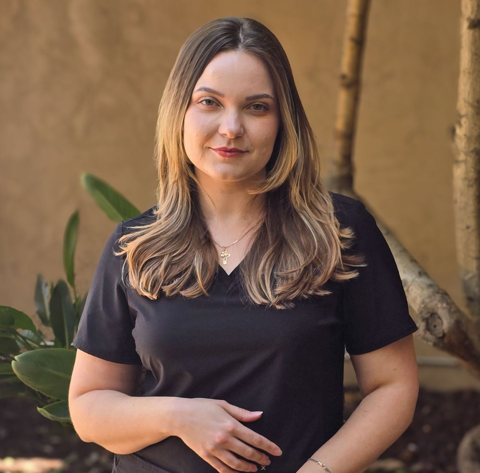 Woman with long, layered hair in a black top, outdoors.