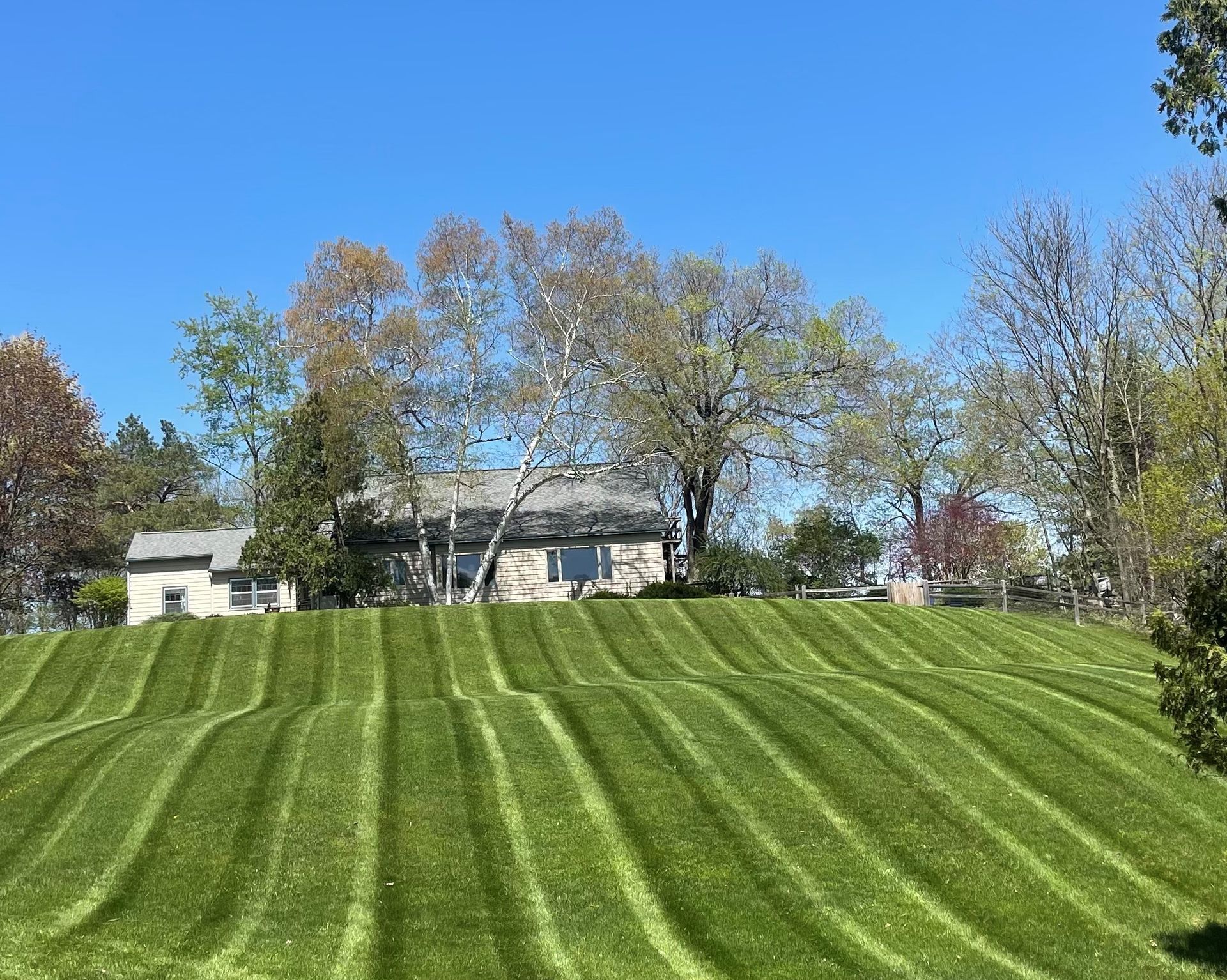 A house is sitting on top of a hill next to a lush green field.