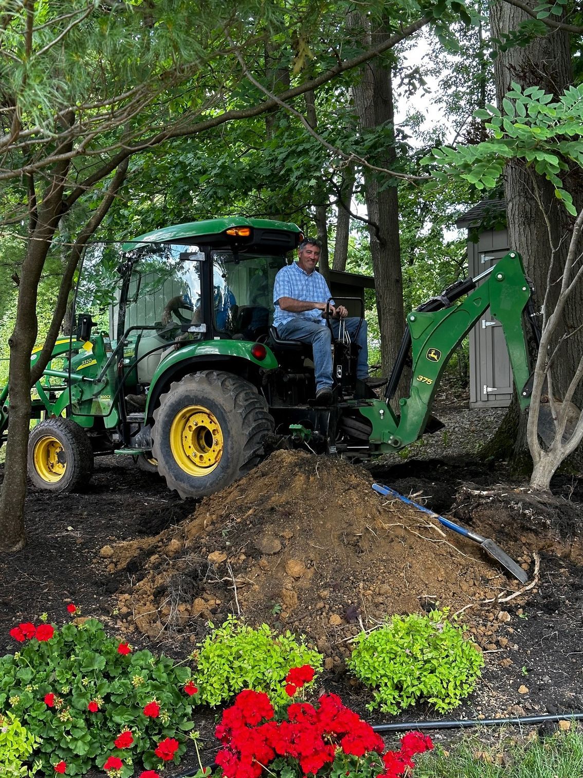A man is driving a green tractor in a garden.
