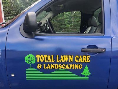 A blue truck with the words total lawn care and landscaping on it
