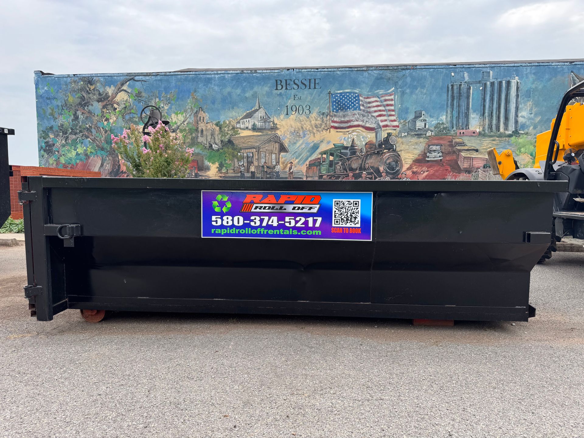 A dumpster is sitting in a snowy alleyway between two brick buildings