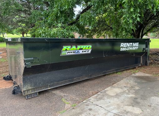 A green dumpster with the word trash on it