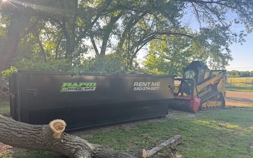 A dumpster filled with concrete and a fence in the background.