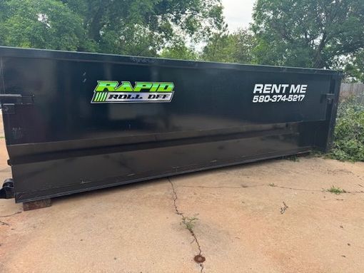 A green dumpster with the word trash on it