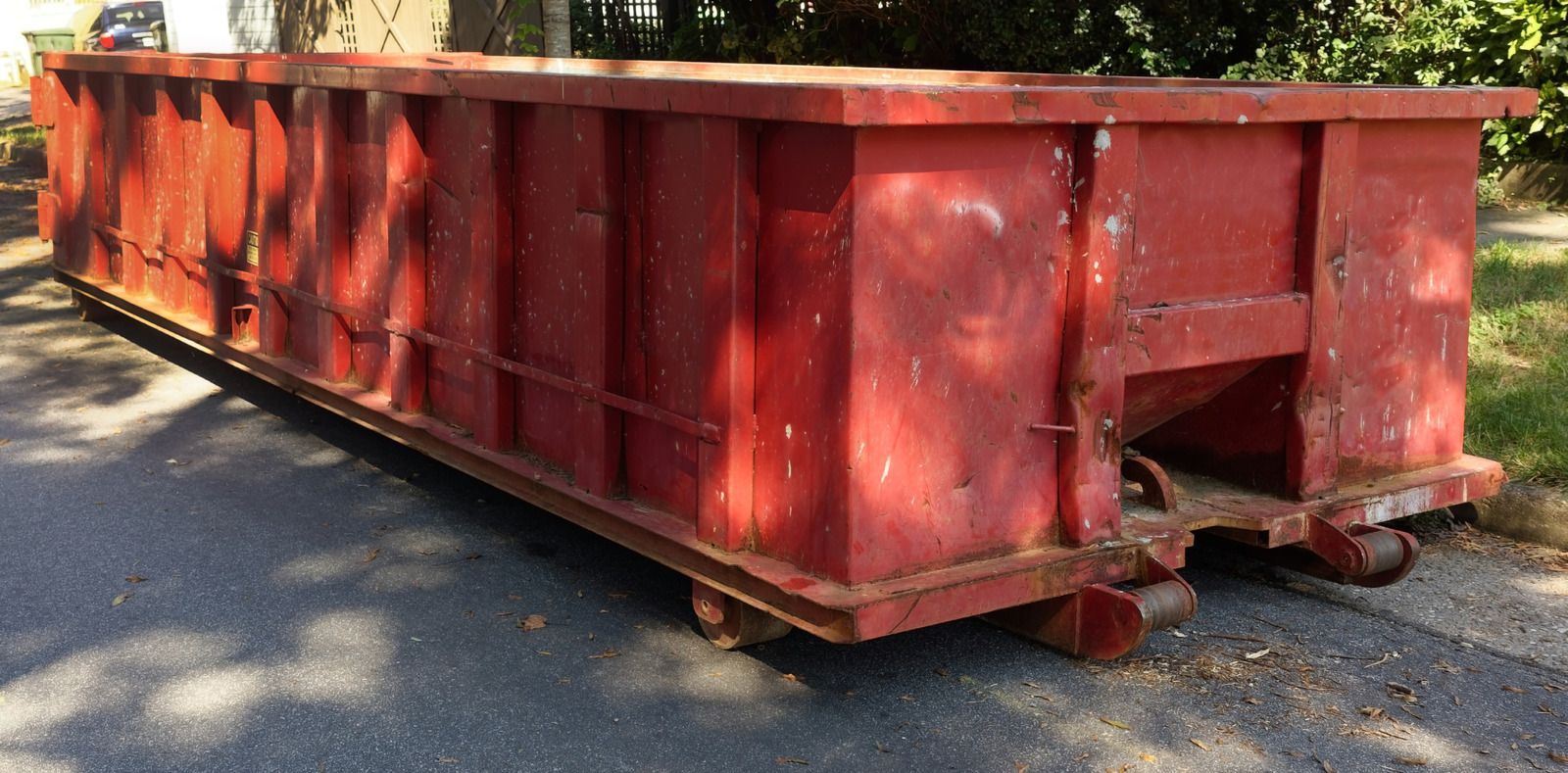 A yellow dumpster filled with trash is sitting on the ground in front of a building.