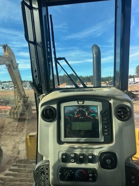 View from inside the cab of a Caterpillar excavator looking out at a construction site with another excavator.