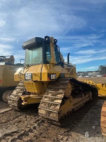 A yellow Caterpillar bulldozer parked on a dirt lot under a blue sky.