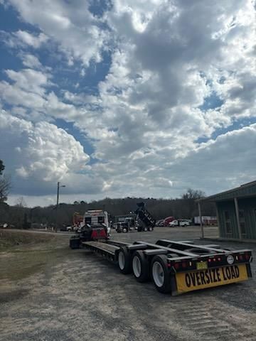 A semi-truck with an empty flatbed trailer labeled 