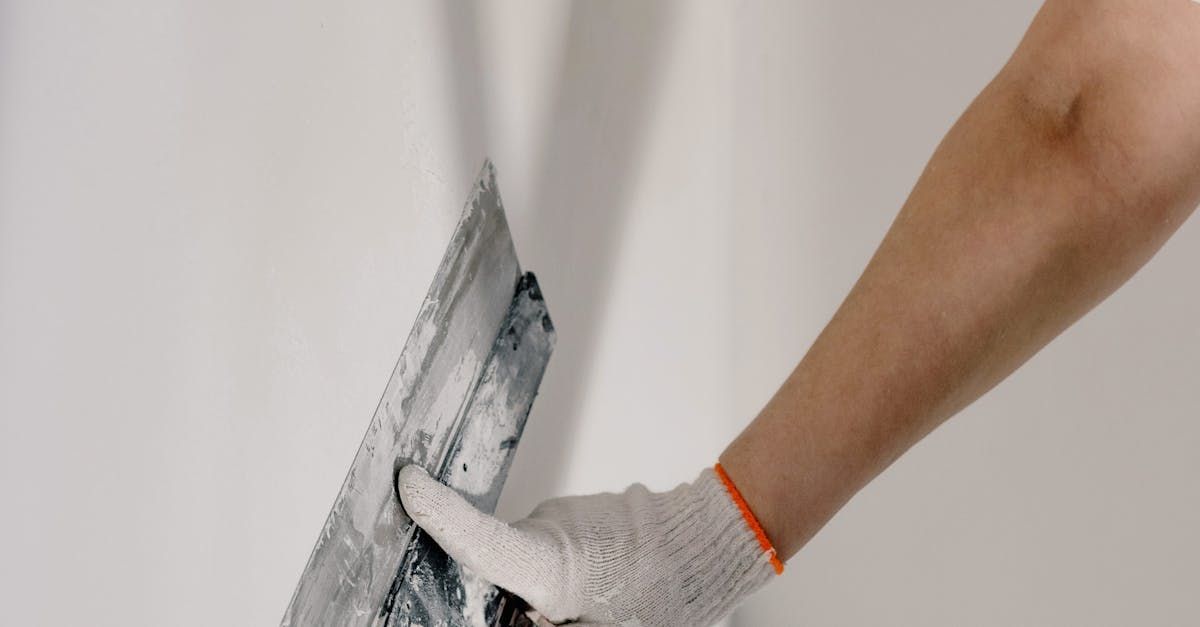 A person is plastering a wall with a trowel.